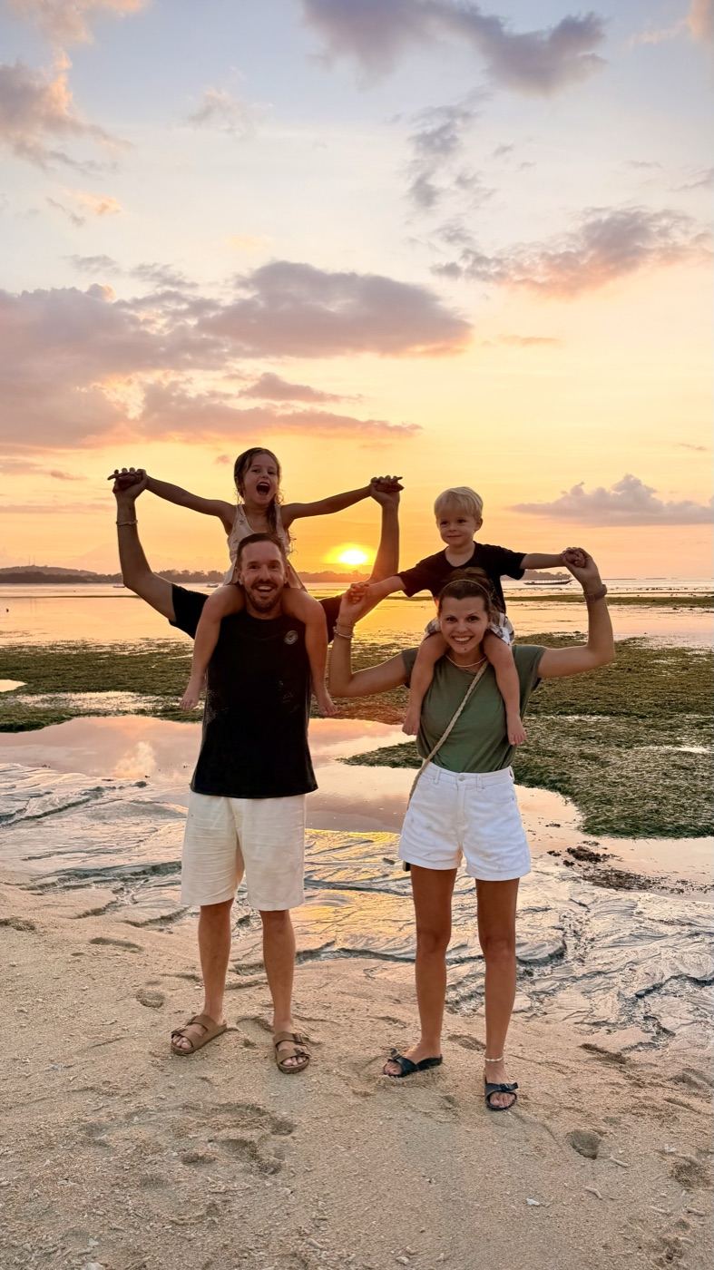 Anna und Oliver mit ihren beiden Kindern auf den Schultern am Strand bei Sonnenuntergang