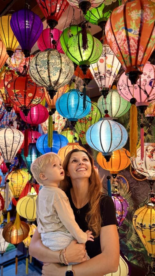 Anna mit Sohn unter bunten Laternen auf einem Nachtmarkt